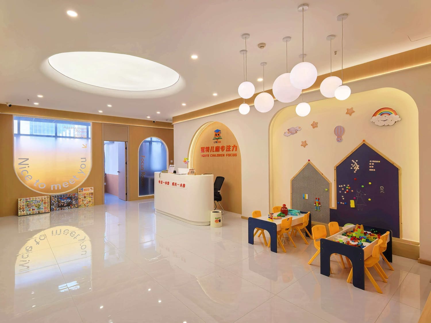 校区大厅实景：左侧磨砂玻璃标着 Assessment Room 测评室，中间拱形门标 Focus Room 专注室，右侧是小组桌与积木墙